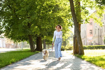 Happy young woman with cute Australian Shepherd dog walking in park