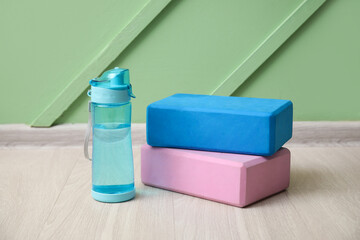 Sports bottle of water and blocks on floor near green wall