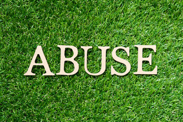 Wood alphabet letter in word abuse on artificial green grass background
