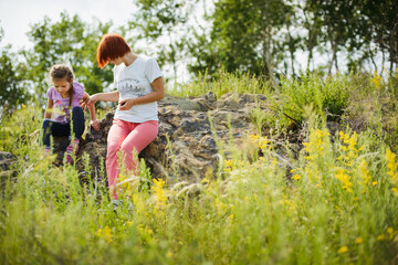 Fototapeta premium Mom and daughter play together in nature, hug and laugh
