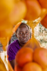 portrait of village African woman, hawker street vendor of fruits, bags of oranges on display...