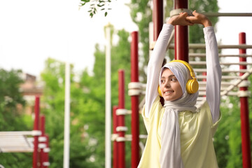 Fototapeta premium Sporty Muslim woman in headphones training outdoors