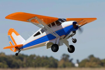 Orange and blue remote controlled airplane soaring over trees