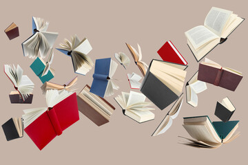 Many different books in air on dark beige background