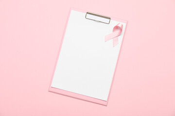 Blank clipboard with silk ribbon on pink background. Breast cancer concept