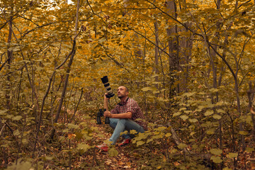 Man using binoculars and camera for bird and animal watching in nature.