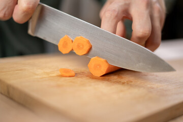 man cutting carrot on wooden board cooking vegetables salad on home kitchen