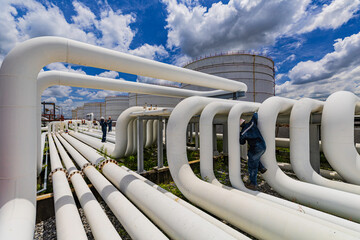 Male worker inspection at steel long pipes and pipe elbow in station oil factory during refinery...