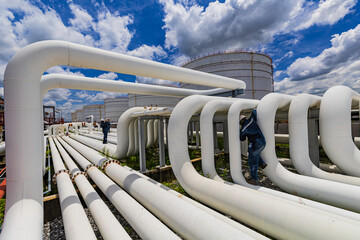 Male worker inspection at steel long pipes and pipe elbow in station oil factory during refinery...