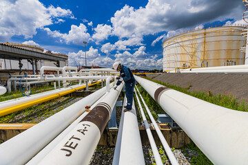 Male worker inspection at steel long pipes and pipe elbow in station oil factory during refinery...