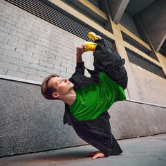 Breakdancer in action, flipping upside down in front of tall urban buildings, his yellow shoes...