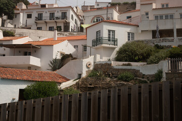 A charming white washed village nestled in a hillside The view from behind a wooden fence is picturesque and serene