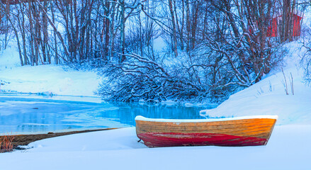 Red wooden boat covered with layers of snow - Beautiful winter landscape with snow covered red...