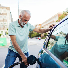 Caucasian senior man refueling his car at a self-service gas station - transportation concepts.
