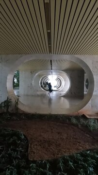 mulher caminhando entre pilotis em pr&eacute;dio residencial em Bras&iacute;lia 