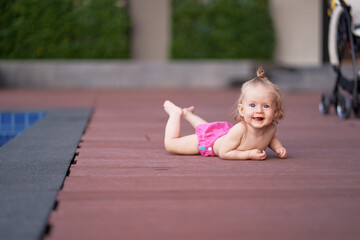 Naklejka premium Little baby girl near swimming pool outdoors.