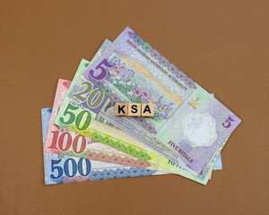 KSA currency notes of 5,10, 20, 50, 100 and 500 denominations with a KSA word written on wooden cubes blocks