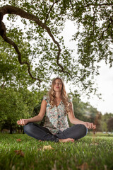 At One with Nature.  A young woman sitting crossed legged in a calm and meditative mood in a rural location.