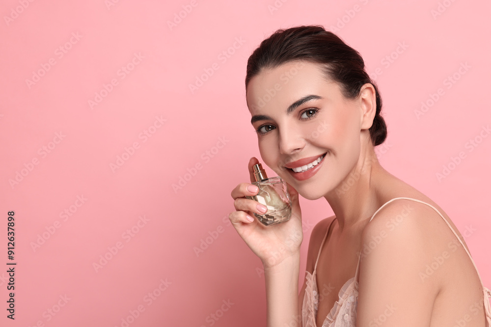 Poster Smiling woman with bottle of perfume on pink background. Space for text