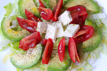 Iceberg lettuce with avocado, peppers, onions and feta cheese with olive oil, healthy salad