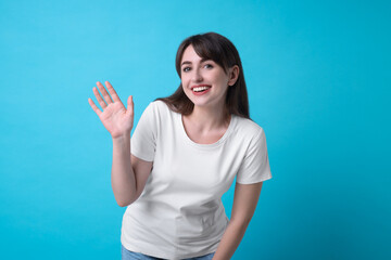 Fototapeta premium Happy woman waving on light blue background