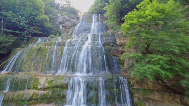 fpv drone flying slowly above multi layered waterfall cascade du herisson Jura at sunrise