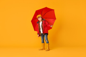 Little boy with red umbrella on orange background