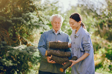 Grandfather with granddaughter on a yard with firewood in hands
