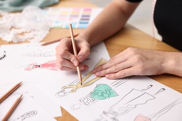Naklejka premium Fashion designer drawing sketch of beautiful dress at wooden table, closeup