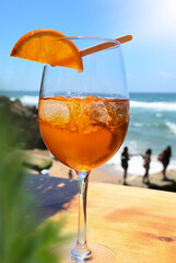 A cocktail with ice cubes and orange at the beach bar, by the sea on vacation, sizzling cool icy drink by the person girl woman party.
