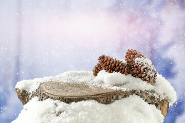 Wooden snow covered tree trunk with copy space and blurry blue winter trees and mountains background.