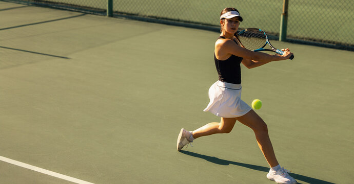 Woman playing tennis with racket and ball on the court during holiday