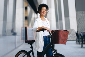 Happy woman with bicycle and basket smiling in an urban European city