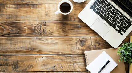 Top view flat lay of a wooden desk with a laptop, notebook, pen, and cup of coffee, with ample copy space