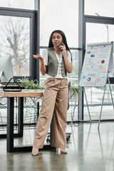 A poised woman discusses business matters while standing in a bright office.