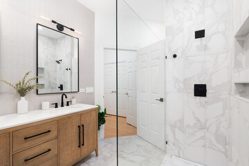 A bathroom detail with a white oak vanity cabinet with a vertical tan subway tile backsplash, white...
