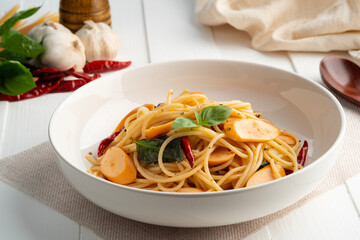 Spaghetti with Sausage and Dried Chili.Spicy stir fried Spaghetti with smoky bite ,garlic and crispy chilli in white plate.