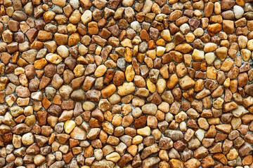 Large natural pebbles arranged to decorate beautiful and strong wall. Yellow and brown pebble stone wall. Surface and Texture background of round stone wall to use as wallpaper. lot of natural stone.