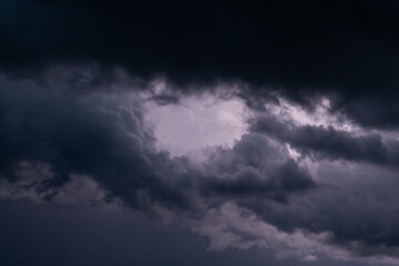 Fototapeta premium Dark blue clouds before a thunder-storm. Gloomy sky with threatening clouds, a storm weather with rain shower and wind in coming nearer