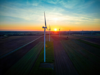 Wind turbines in a field just before sunrise, representing the concept of renewable energy and...