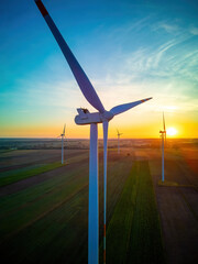 Wind turbines in a field just before sunrise, representing the concept of renewable energy and...