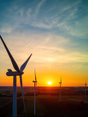 Wind turbines in a field just before sunrise, representing the concept of renewable energy and...