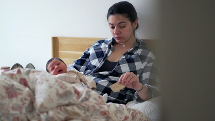 Mother with newborn baby resting on bed, looking tired and contemplative, highlighting the...