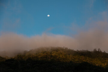 Montanha no pôr do sol com névoa e lua cheia