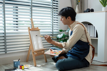 Young Artist Painting on Canvas in Modern Home Studio with Natural Light and Creative Atmosphere