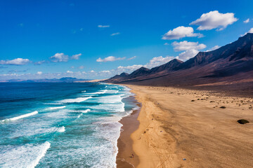 Amazing Cofete beach with endless horizon. Volcanic hills in the background and Atlantic Ocean. Cofete beach, Fuerteventura, Canary Islands, Spain. Playa de Cofete, Fuerteventura, Canary Islands.