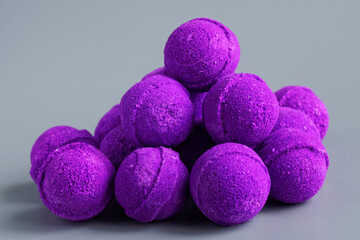 A bunch of neon purple bath bombs with sea salt lie on a light green background. Copy space. Photo. Selective focus