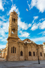 A small building with a blue door sits in front of a large Mosque with a tall tower in Nicosia,...