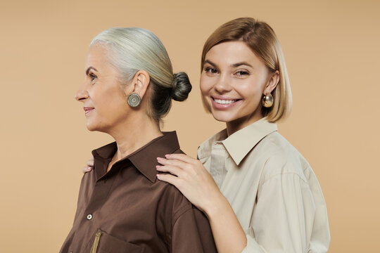 A mature woman stands proudly beside her smiling adult daughter.