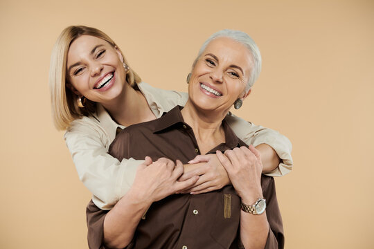 A mother and daughter share laughter and affection in a cozy environment.